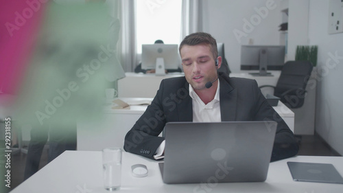 Man sit at a table and work at a laptop.