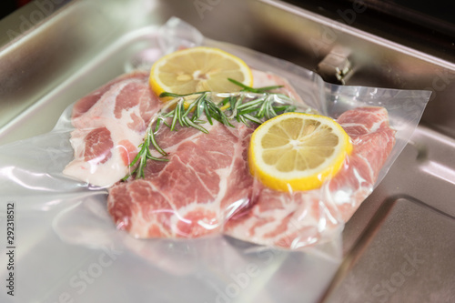 Sous vide steak with rosemary and lemons in vacuumed package.