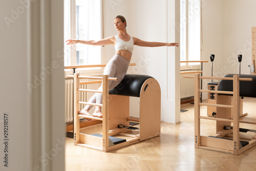 Beautiful Caucasian woman doing pilates exercise using equipment.