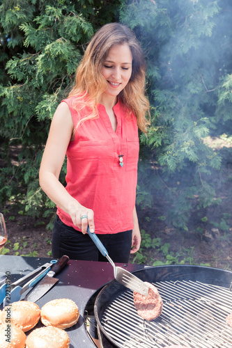 Happy woman making barbecue in the backyard.