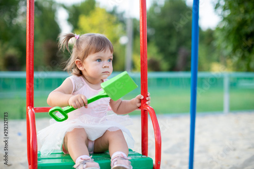 little baby girl on the swing in park playground