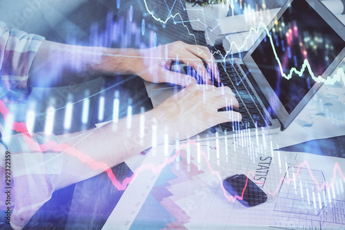 Double exposure of stock graph with businessman typing on computer in office on background. Concept of hard work. © peshkova