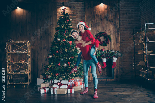 Full length body size view of nice attractive lovely cheerful cheery spouses having fun spending winter December domestic fest in decorated lights loft industrial brick wood style interior