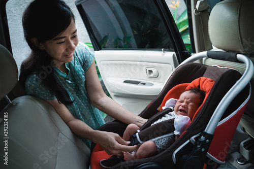 little daughter crying when put in the car seat by her mother before to journey © Odua Images