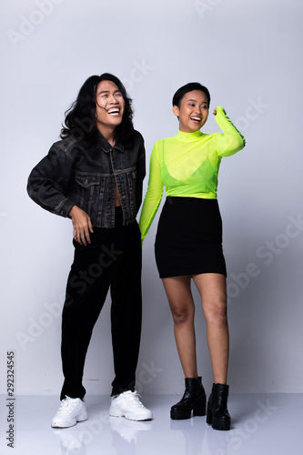 Two Fashion Young Unisex Asian Woman and man beautiful make up fashion wear Jean jacket and green neon shirt, high platform shoes and nose ring. Studio Lighting gray Background isolated copy space photo