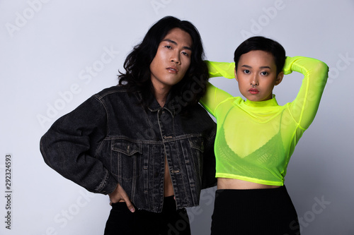 Two Fashion Young Unisex Asian Woman and man beautiful make up fashion wear Jean jacket and green neon shirt, high platform shoes and nose ring. Studio Lighting gray Background isolated copy space photo