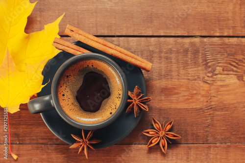 Grey cup of coffee, cinnamon, anise, yellow maple leaf on dark wooden table. Autumn menu concept. Fall, expresso, spices, coffee shop, break