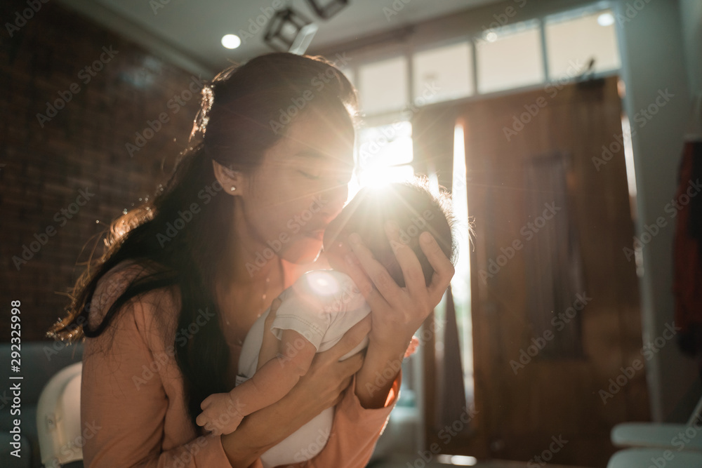 mother kissing her little daughter when carrying in the home