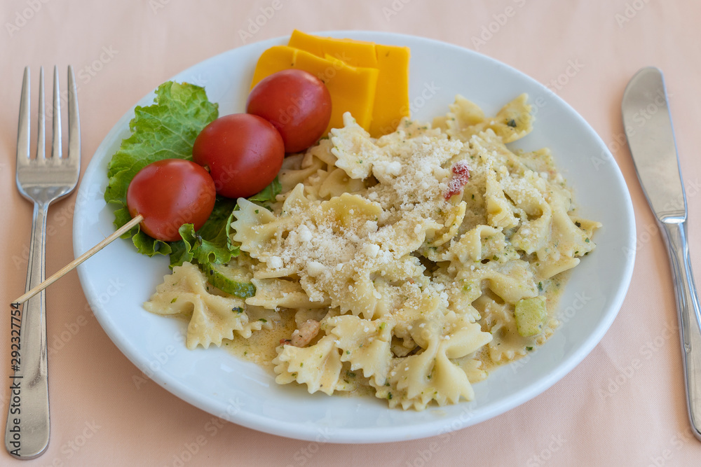 Pasta farfalle with cherry tomato and cheese in white plate, closeup Pasta farfalle with cherry tomato and cheese in white plate, closeup
