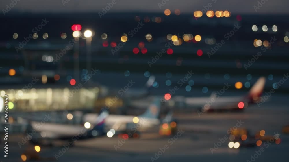 A blurred night airport area with a multitude of light spots - car lights, plane lights, building lights