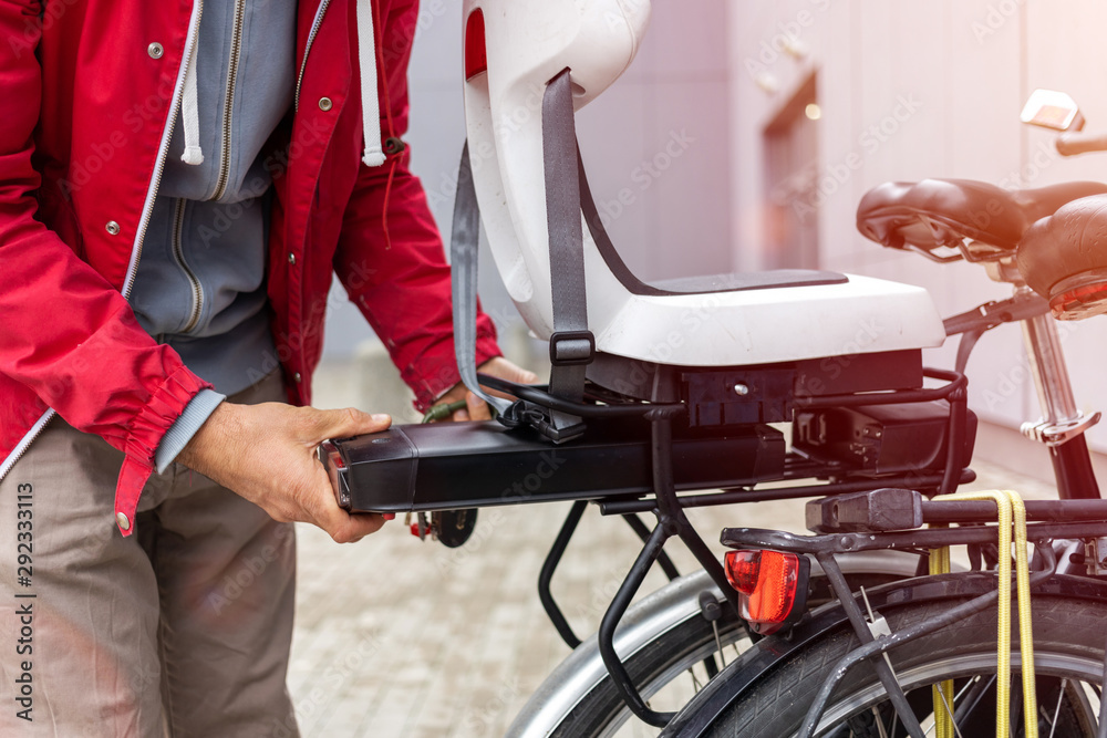 Man inserting battery in backseat of electric bicycle Man inserting battery in backseat of electric bicycle