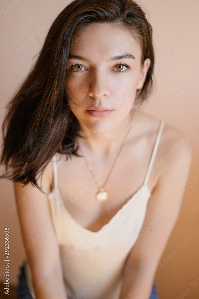 Beautiful young woman posing on beige wall background. Beautiful young woman posing on beige wall background.