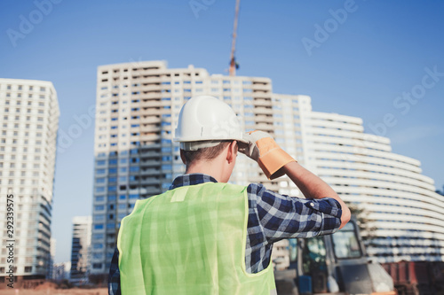 Builder in a helmet looks at the new building