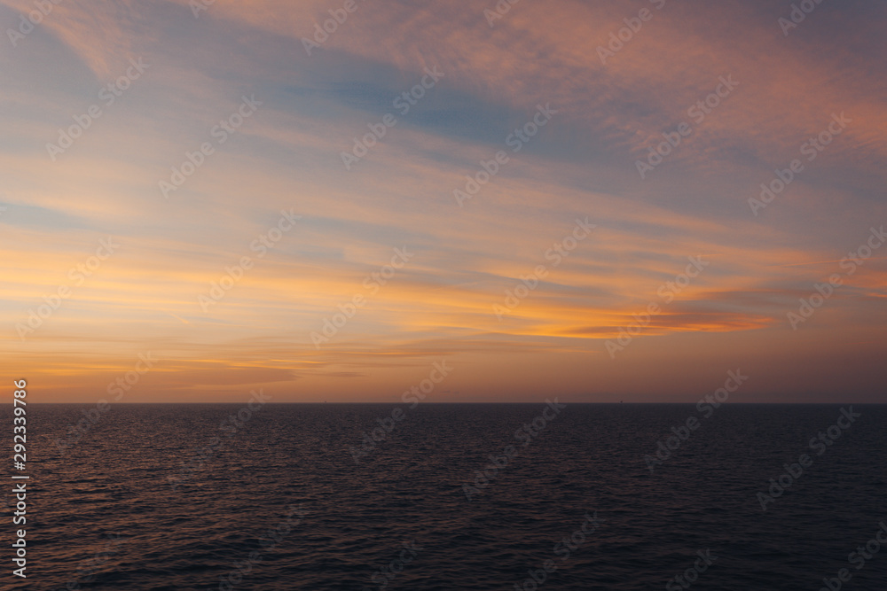 Horizon of the sea and orange-colored clouds after sunset