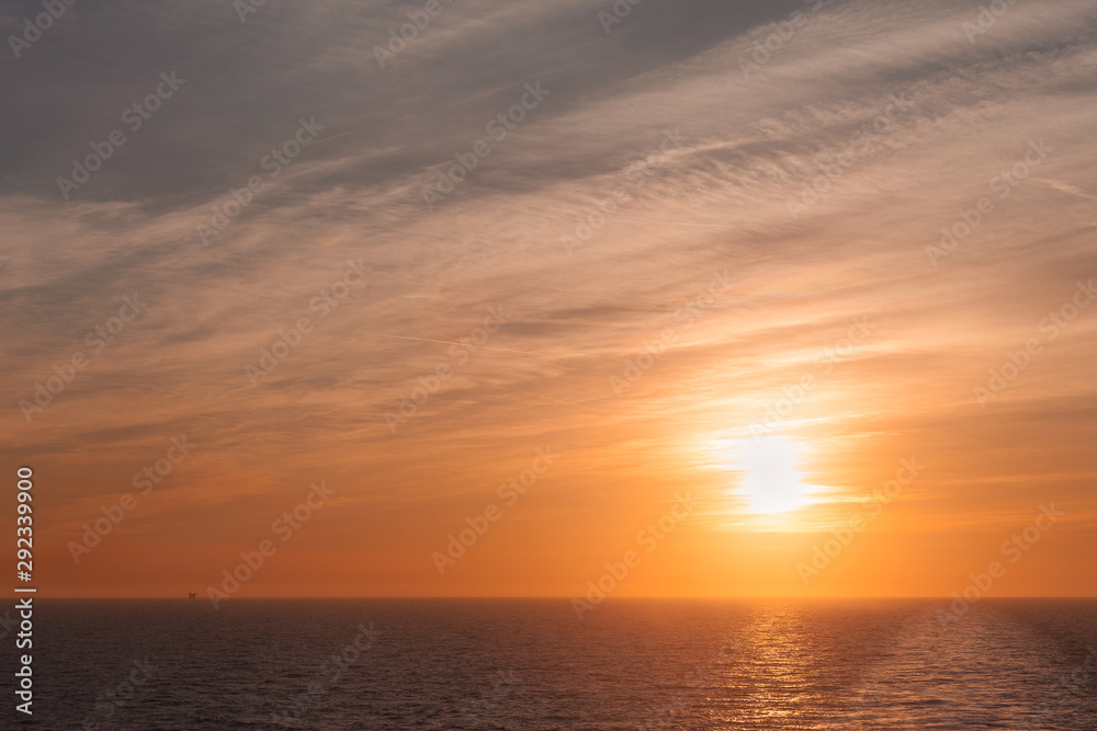 Sunset and colorful sky on the sea with a wake left by a cruise ship