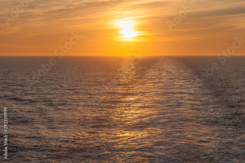 Sunset on the sea where you can see the wake left by a cruise ship