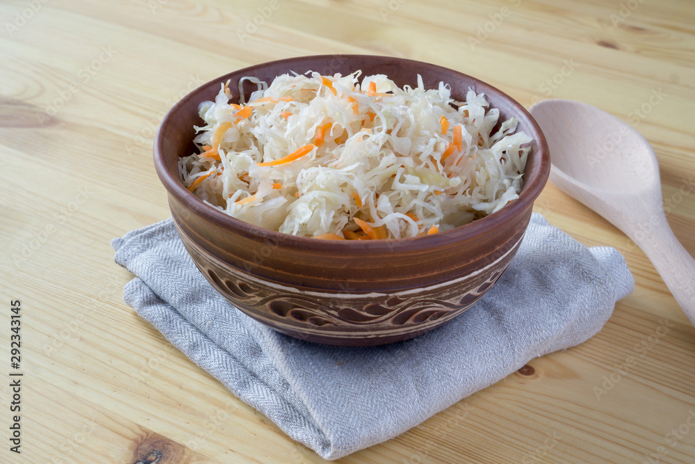 Sour cabbage fermented sauerkraut with carrot in a bowl. Marinated cabbage on wooden background Sour cabbage fermented sauerkraut with carrot in a bowl. Marinated cabbage on wooden background
