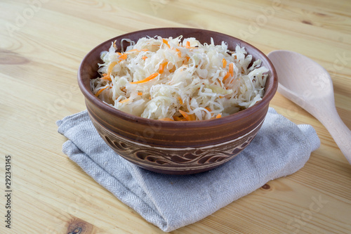 Sour cabbage fermented sauerkraut with carrot in a bowl. Marinated cabbage on wooden background