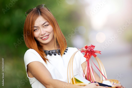 closeup outdoor portrait of smiling happy attractive asian woman holding gift box. Celebration concept