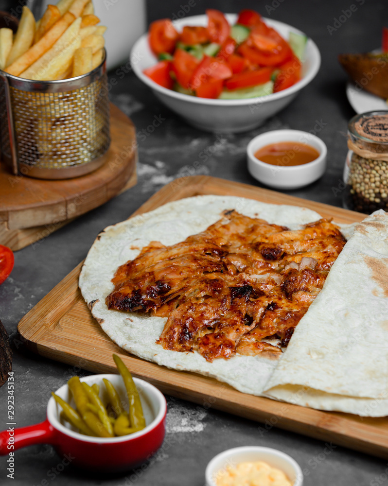 Grilled chicken slices inside of lavash wrap served with french fries