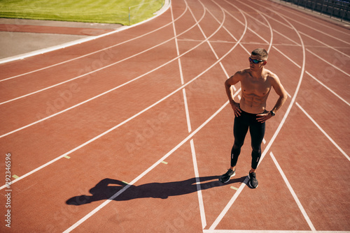 Above view image of young athlete man posing on racetrack at stadium. Professional shirtless sportsman during training session. People, sport and healthy lifestyle