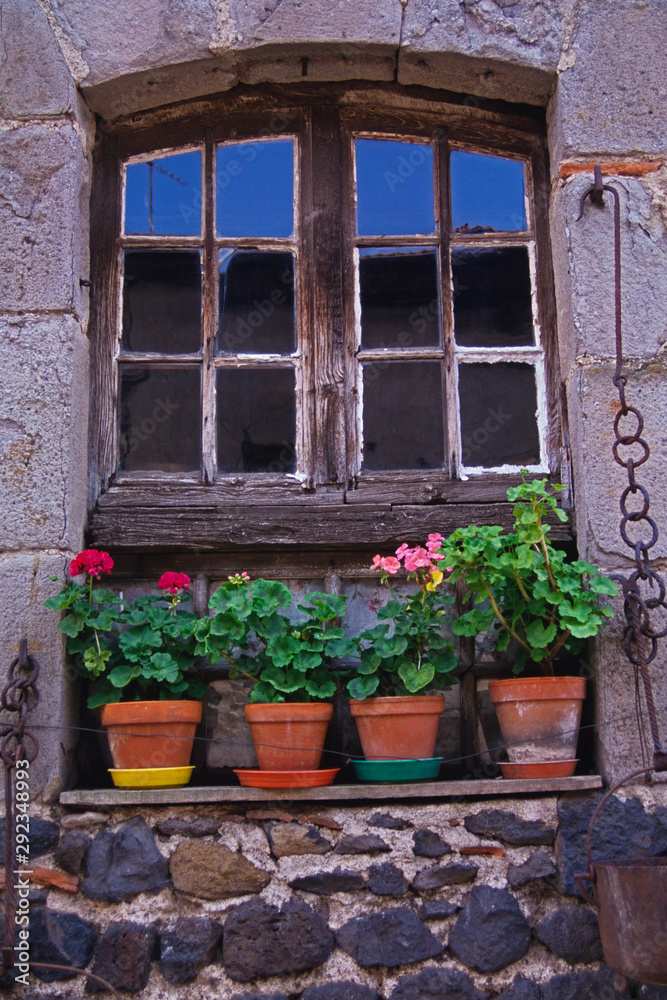 An old window frame decorated with potted Geraniums in Normandy France