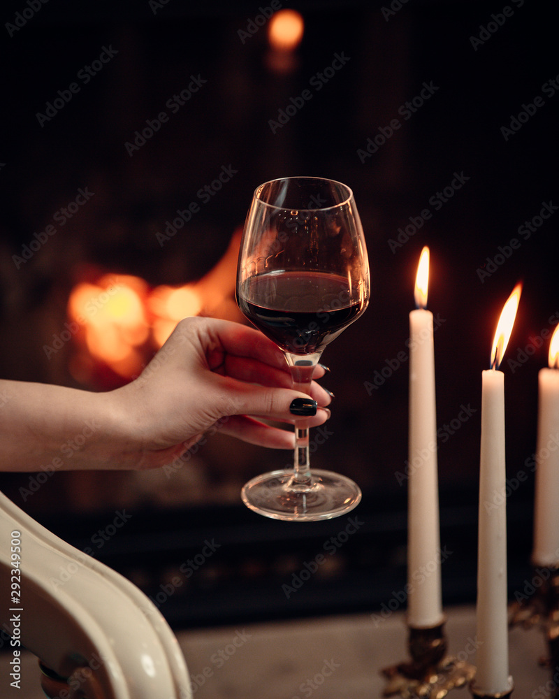 A glass of red wine surrounded with candles in romantic atmosphere