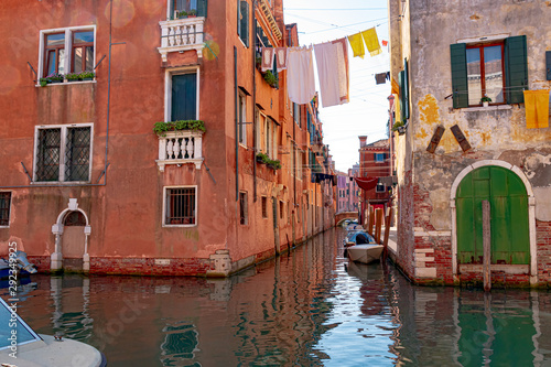 Venice, Veneto, Italy - A narrow canal in Venice is traditionally used to dry clothes by tying a line to the house and boats can ride underneath.