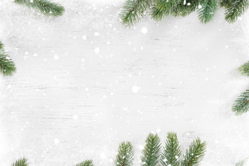 Pine leaves decorated as a frame on a white wooden background  with snowflakes. Merry Christmas and winter holiday background.