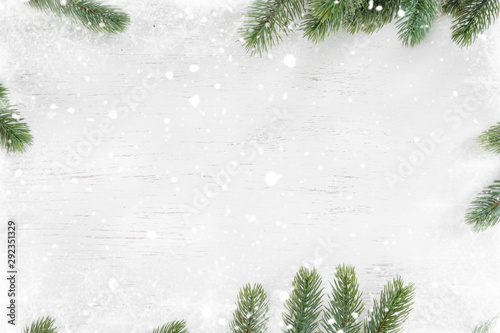Pine leaves decorated as a frame on a white wooden background  with snowflakes. Merry Christmas and winter holiday background.