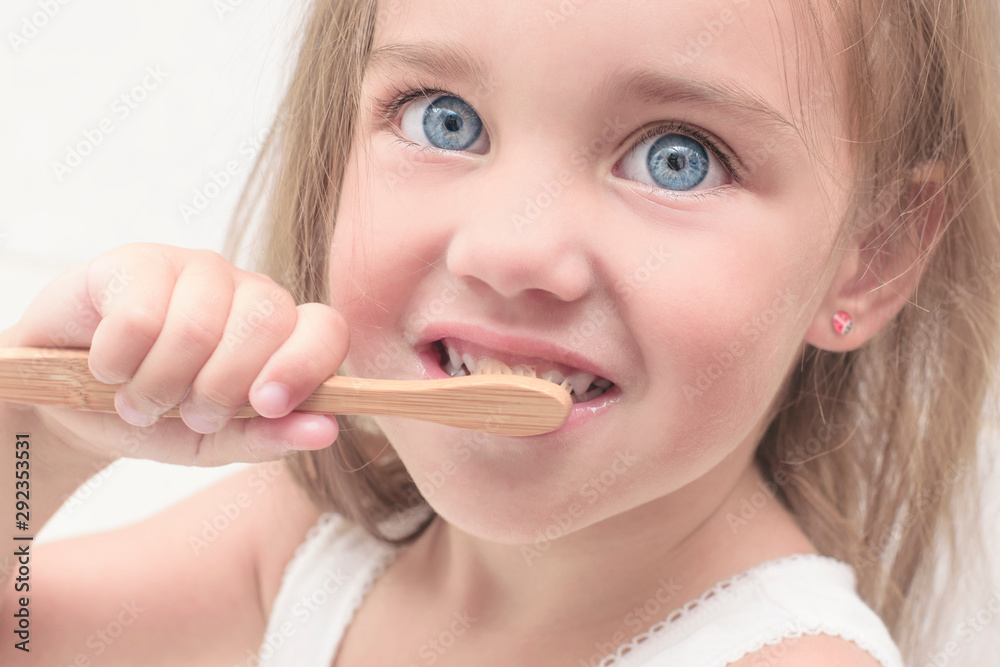 Little girl learns to brush her teeth. Dental care and health. Dental health concept, dentistry, hygiene. Bamboo toothbrush..Face close up. Little girl learns to brush her teeth. Dental care and health. Dental health concept, dentistry, hygiene. Bamboo toothbrush..Face close up.