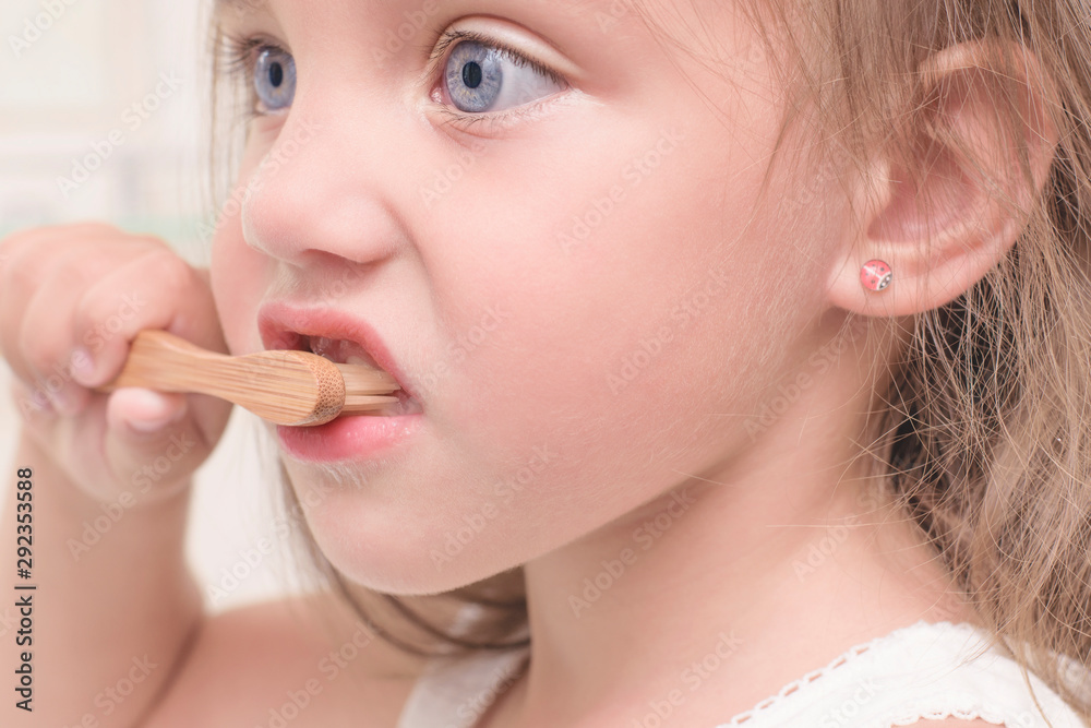 A child brushes his teeth with a bamboo toothbrush. Close-up face. A child brushes his teeth with a bamboo toothbrush. Close-up face.