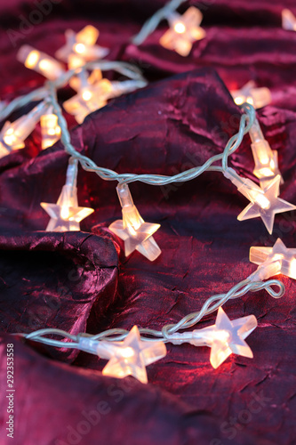 christmas lights with stars on red silk cloth as a christmas background