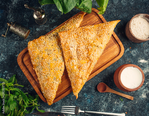 Triangled-shape bourekas baked pie with sesame seeds photo