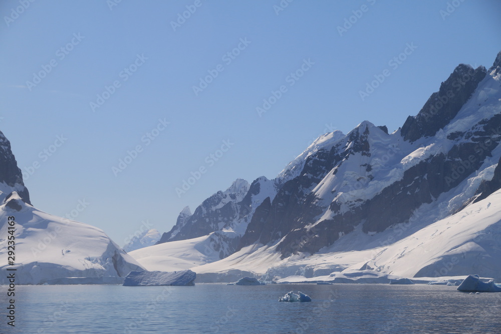 spokojne zimne wody pomiędzy ośnieżonymi skałami u wybrzeży antarktydy w piękny słoneczny dzień