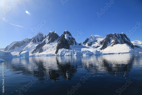 spokojne zimne wody pomiędzy ośnieżonych skałami u wybrzeży antarktydy w piękny słoneczny dzień © KOLA  STUDIO