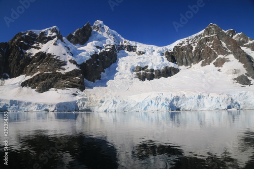 spokojne zimne wody pomiędzy ośnieżonych skałami u wybrzeży antarktydy w piękny słoneczny dzień © KOLA  STUDIO