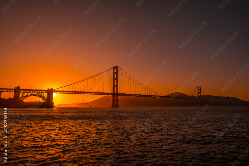 Red sunset at the Golden Gate of San Francisco with the sun hiding on the bridge. United States