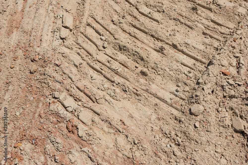 Fototapeta premium Crawler traces on yellow mud ground surface closeup background pattern