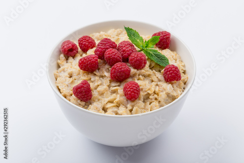 Oatmeal porridge with fresh raspberries and mint on white background NOT isolated