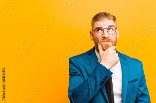 Fotografia young red head businessman thinking, feeling doubtful and confused, with differe