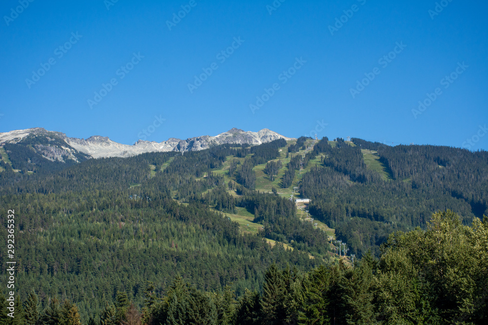 Whistler Mountain in British Columbia, Canada in the summer sun and blue sky looking at sky lift and runs used for mountain biking and hiking.