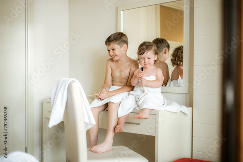 Cute toddler boy brushing his teeth after having a bath. Boy after evening before sleep rituals.