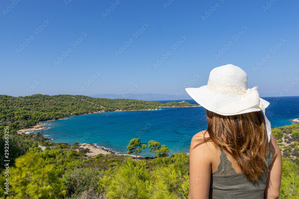 Young woman with hat looking at a beach on Spetses ISland near Hydra in Greece