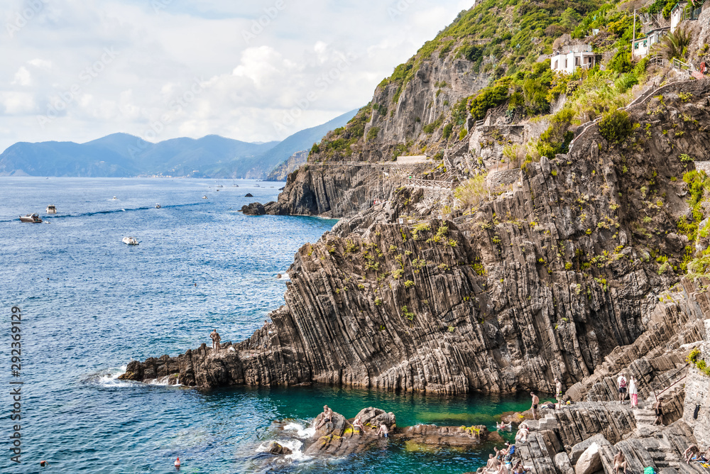 Riomaggiore, Cinque Terre, Italy - August 17, 2019: A beach full of tourists in the summer season at a popular resort in Europe. Rocky coast of liguria