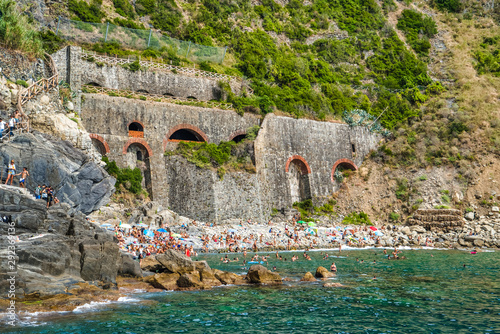 Obraz na płótnie Riomaggiore, Cinque Terre, Italy - August 17, 2019: A beach full of tourists in the summer season at a popular resort in Europe. Rocky coast of liguria w salonie