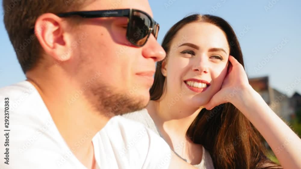 Portraits of a young cheerful couple. Romantic couple talking and sitting against the blue sky. Happy together. Close up shot. Portraits of a young cheerful couple. Romantic couple talking and sitting against the blue sky. Happy together. Close up shot.