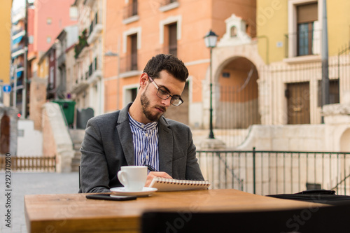 Young businessman is writing in his notebook in a bar terrace