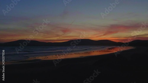 Slow motion of the sea movement and colorful sunset reflected on the beach sand photo