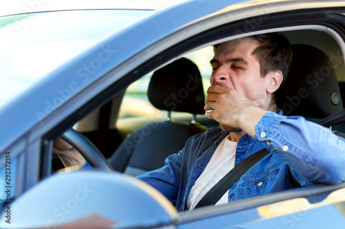 Canvas Print Man is yawning behind steering wheel of car